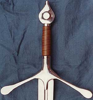 Polished hilt with downturned spatulated or spoon ended terminals, featuring a disc pommel wth a protrusion for the tang to pass through at the top giving a tear drop profile.