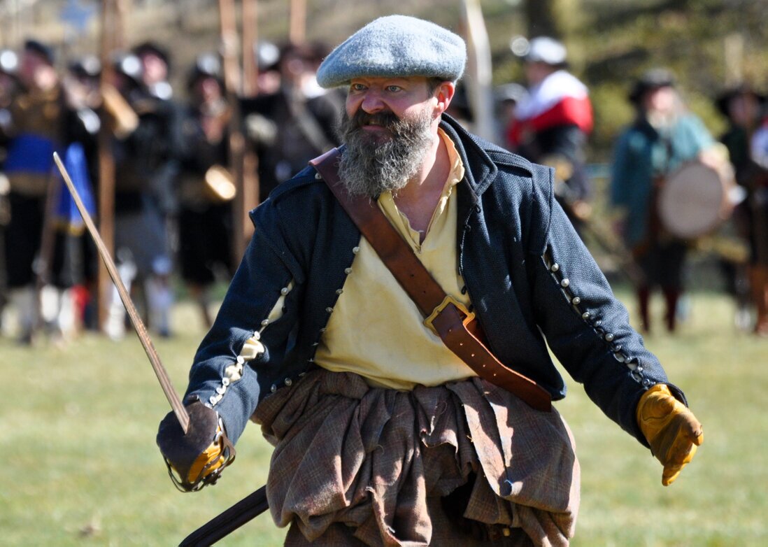 Highlander charging in blue bonnet with slash sleeved doublet Plaid and sword .